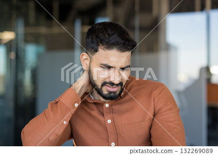 Young man experiencing discomfort and muscle tension in his neck and shoulder due to stress and long working hours, needing relief from chronic pain and discomfort Young man experiencing discomfort and muscle tension in his neck and shoulder due to stress and long working hours, needing relief from chronic pain and discomfort 132269089