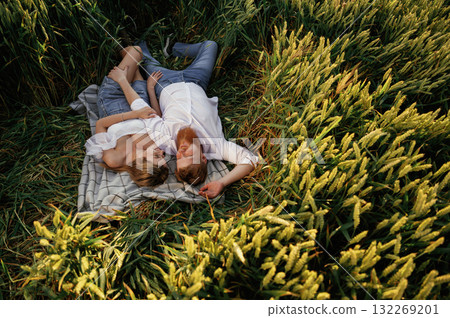 Resting, lying down, top view. Lovely couple are on the green agricultural field together 132269201