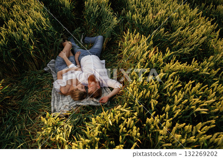 Resting, lying down, top view. Lovely couple are on the green agricultural field together 132269202