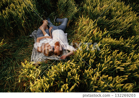 Resting, lying down, top view. Lovely couple are on the green agricultural field together 132269203