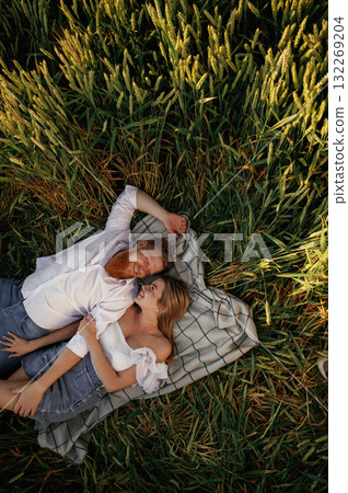 On the blanket, lying down, top view. Lovely couple are on the green agricultural field together 132269204