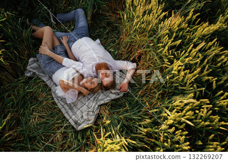On the blanket, lying down, top view. Lovely couple are on the green agricultural field together 132269207