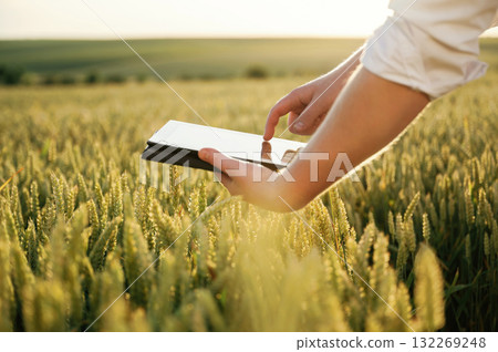 Black digital tablet. Man in white shirt is on the agricultural field Black digital tablet. Man in white shirt is on the agricultural field 132269248