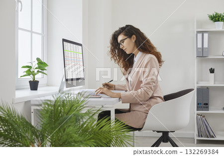 Young business woman accountant working on a pc computer with tables and charts at office. 132269384