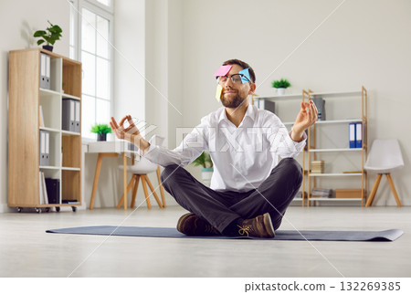 Funny man with sticky notes on face sitting on floor in office, doing meditation, and relaxing 132269385