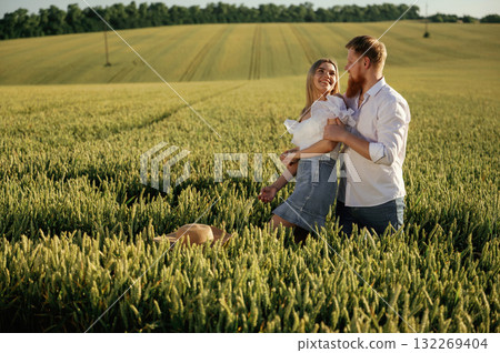 Summertime wellness, happiness. Lovely couple are on the green agricultural field together Summertime wellness, happiness. Lovely couple are on the green agricultural field together 132269404