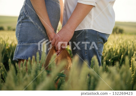 Close up view, holding each other's hands. Lovely couple are on the green agricultural field together 132269423