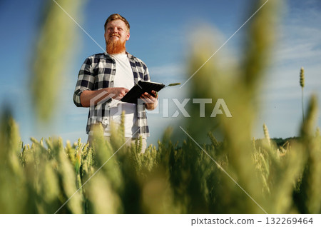 Process of quality control, with digital tablet. Man in white shirt is on the agricultural field Process of quality control, with digital tablet. Man in white shirt is on the agricultural field 132269464