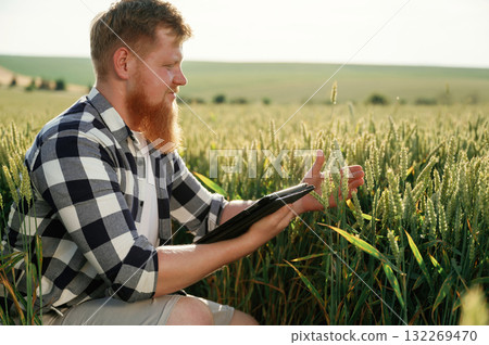 Checking the growth process, with digital tablet. Man in white shirt is on the agricultural field 132269470