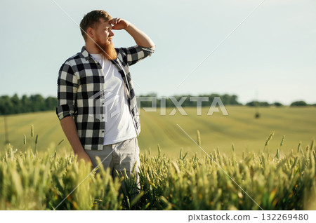 Beautiful view. Man in white shirt is on the agricultural field Beautiful view. Man in white shirt is on the agricultural field 132269480