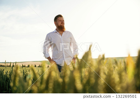 Beautiful view. Man in white shirt is on the agricultural field Beautiful view. Man in white shirt is on the agricultural field 132269501
