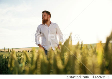 Beautiful view. Man in white shirt is on the agricultural field Beautiful view. Man in white shirt is on the agricultural field 132269502