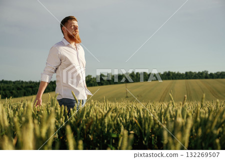 Having a walk. Man in white shirt is on the agricultural field Having a walk. Man in white shirt is on the agricultural field 132269507