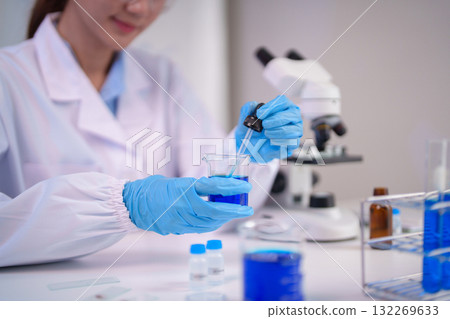 Asian woman scientist performs laboratory chemical experiment precise liquid handling modern research facility medical scientific discovery development 132269633