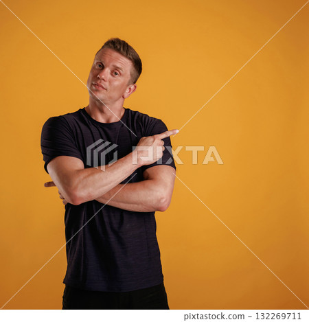 Showing to the side, pointing. Man is against background in the studio 132269711