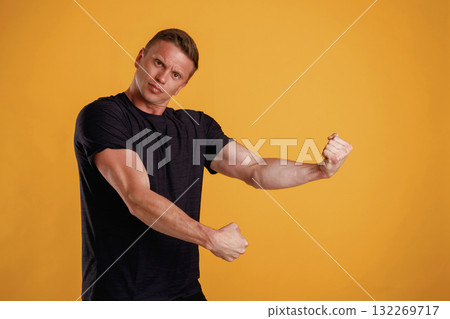 Strong arms, showing muscles. Man is against background in the studio Strong arms, showing muscles. Man is against background in the studio 132269717