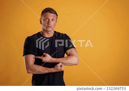 Biceps, pointing on it by finger. Man is against background in the studio Biceps, pointing on it by finger. Man is against background in the studio 132269753