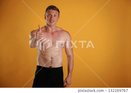 Without shirt, showing thumb up, smiling. Man is against background in the studio Without shirt, showing thumb up, smiling. Man is against background in the studio 132269767