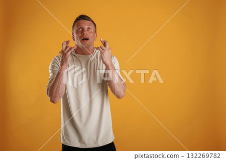 Fingers crossed, hoping for the luck. Man is against background in the studio 132269782