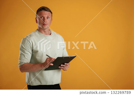 With notepad and pen. Man is against background in the studio With notepad and pen. Man is against background in the studio 132269789