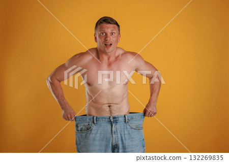 Weight loss, shocked by results, big and huge pants or jeans. Man is against background in the studio 132269835