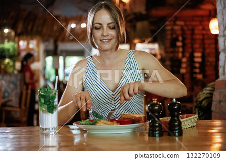 Front view. Woman is in the restaurant with food and drink Front view. Woman is in the restaurant with food and drink 132270109