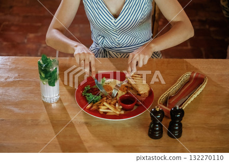 Egg and French fries. Close up view woman that is sitting in restaurant and eating food 132270110