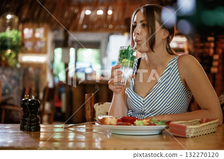 Drinking the mojito. Woman is in the restaurant with food and drink 132270120