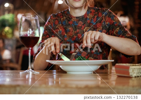 Uses a fork and a knife. Woman is in the restaurant with food and drink Uses a fork and a knife. Woman is in the restaurant with food and drink 132270138