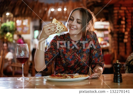 Delicious slice of pizza. Woman is in the restaurant with food and drink Delicious slice of pizza. Woman is in the restaurant with food and drink 132270141