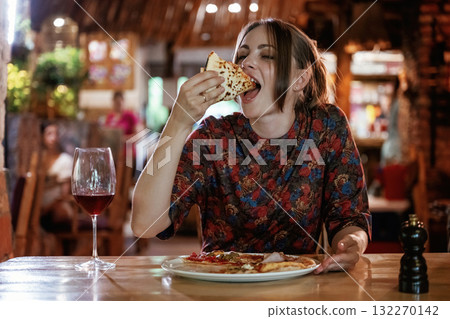 Delicious slice of pizza. Woman is in the restaurant with food and drink Delicious slice of pizza. Woman is in the restaurant with food and drink 132270142