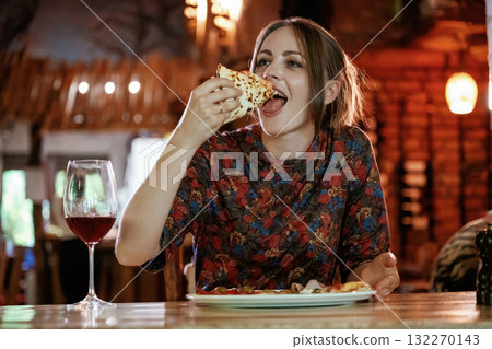 Delicious slice of pizza. Woman is in the restaurant with food and drink Delicious slice of pizza. Woman is in the restaurant with food and drink 132270143