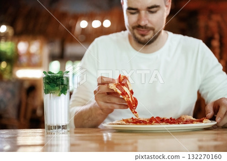 Positive, enjoying. Man is sitting in the restaurant and eating a pizza Positive, enjoying. Man is sitting in the restaurant and eating a pizza 132270160