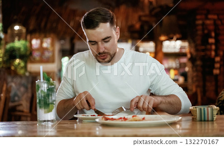 Man is sitting in the restaurant and eating a pizza Man is sitting in the restaurant and eating a pizza 132270167