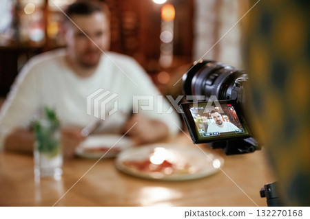 Camera is filming him. Man is sitting in the restaurant and eating a pizza Camera is filming him. Man is sitting in the restaurant and eating a pizza 132270168