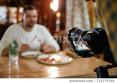 Camera is filming him. Man is sitting in the restaurant and eating a pizza Camera is filming him. Man is sitting in the restaurant and eating a pizza 132270169