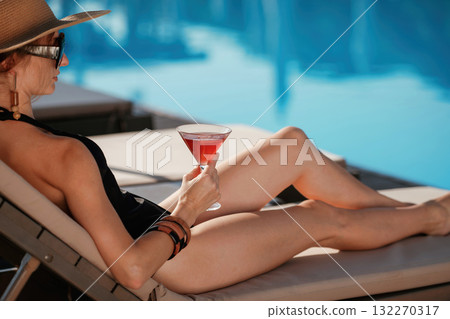 Glass of cocktail in hand. Beautiful young woman is at resort, vacation Glass of cocktail in hand. Beautiful young woman is at resort, vacation 132270317