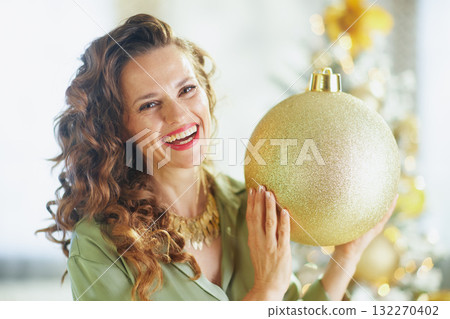 Cheerful Woman with Shimmering Gold Christmas Ornament Cheerful Woman with Shimmering Gold Christmas Ornament 132270402