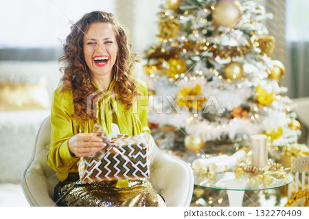 Smiling Woman Unwrapping a Festive Christmas Present Smiling Woman Unwrapping a Festive Christmas Present 132270409