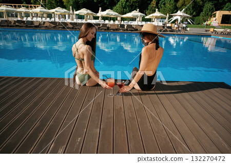 Back view. Two beautiful women are resting near the pool 132270472