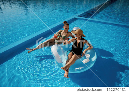 Chilling in the pool. Two beautiful women are resting Chilling in the pool. Two beautiful women are resting 132270481