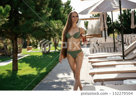 Front view, standing. Beautiful young woman is at resort, vacation 132270504