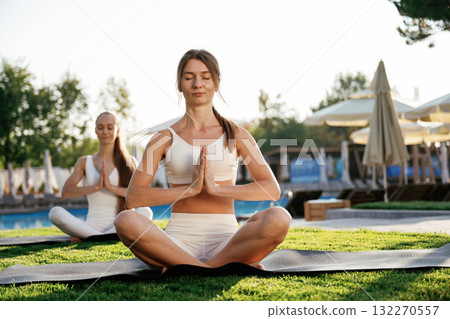 Meditation practice in lotus pose. Two fitness women are together outdoors, conception of sport Meditation practice in lotus pose. Two fitness women are together outdoors, conception of sport 132270557