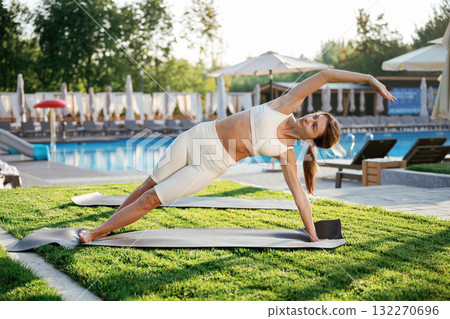 Stretching exercise. Fitness woman is outdoors, beautiful vacation place Stretching exercise. Fitness woman is outdoors, beautiful vacation place 132270696