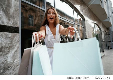 Extremely happy with new stuff. Stylish woman is with shopping bag outdoors near the building Extremely happy with new stuff. Stylish woman is with shopping bag outdoors near the building 132270765
