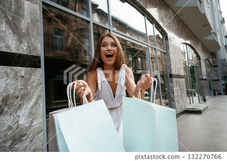 Showing the new stuff, smiling. Stylish woman is with shopping bag outdoors near the building 132270766