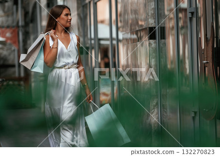 On the street. Stylish woman is with shopping bag outdoors near the building On the street. Stylish woman is with shopping bag outdoors near the building 132270823