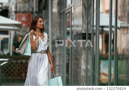 On the street. Stylish woman is with shopping bag outdoors near the building On the street. Stylish woman is with shopping bag outdoors near the building 132270824