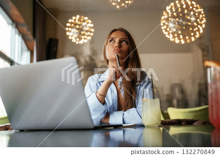 Cocktail is on the table. Beautiful woman with laptop is in the bar 132270849