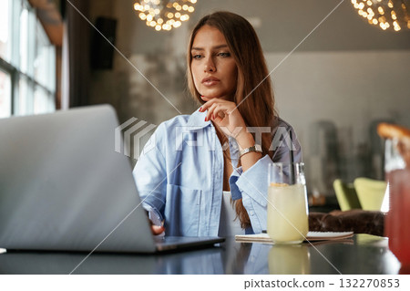 Cocktail is on the table. Beautiful woman with laptop is in the bar 132270853